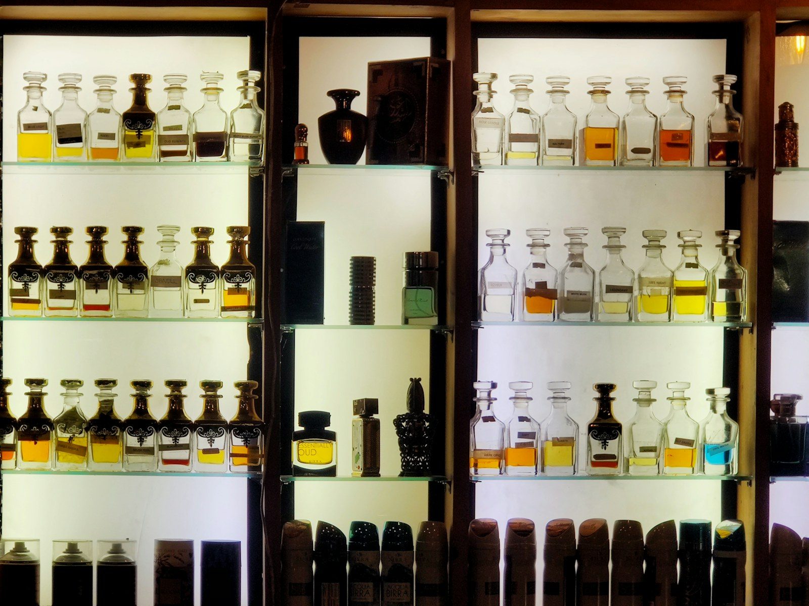 Traditional perfume bottles displayed on illuminated glass shelves